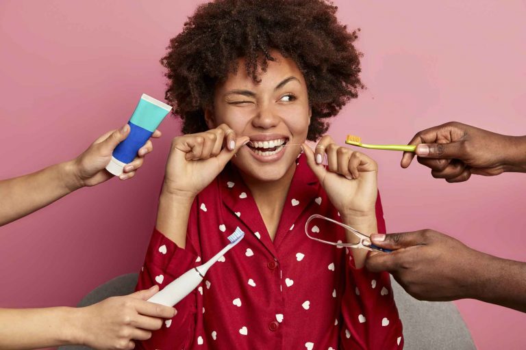 a woman flossing her teeth while people hold toothpaste and toothbrushes around her