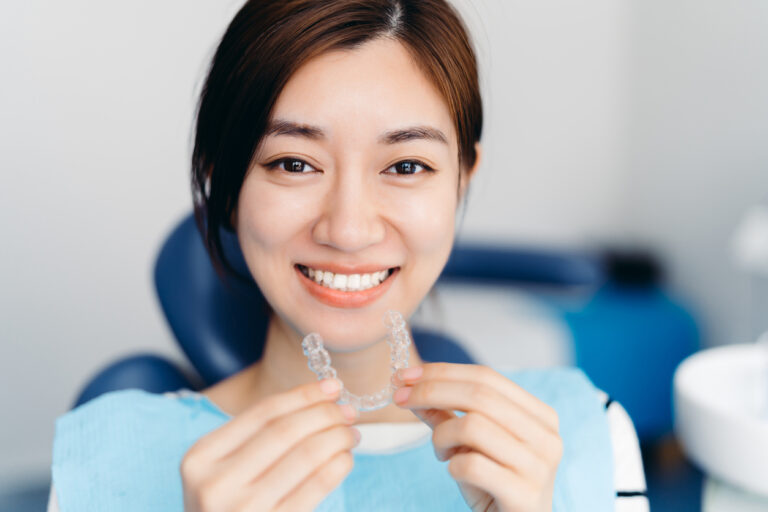 smiling woman holding an invisalign aligners
